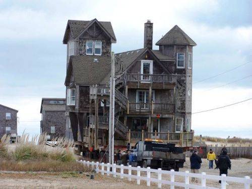 Beach house with people in foreground Serendipity takes a journey to its new lot in Rodanthe on Hatteras Island, NC.